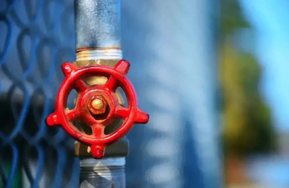 Close-up of a red plumbing shut-off valve on a metal pipe