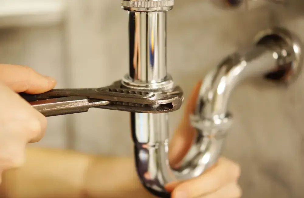 Plumber tightening and inspecting a sink drain pipe connection