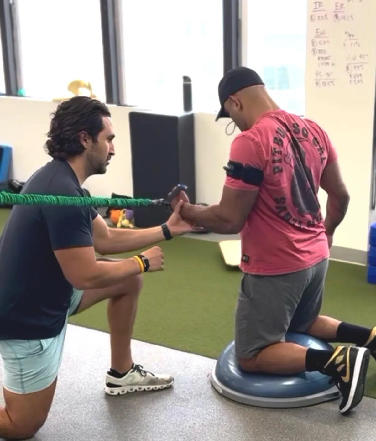 Dr. Brian, physical therapist in St. Pete working with a injured athlete perform a shoulder exercise.