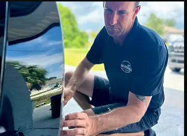 A family sedan with doors open, technicians cleaning both interior and exterior in a spotless service bay, with bright lighting highlighting the car’s renewed appearance and attention to detail.