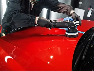 A luxury SUV being detailed in a residential driveway, with a technician using a high-pressure washer, surrounded by lush greenery and sunlight, emphasizing convenience and premium service at home.