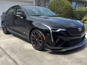 A family sedan with doors open, technicians cleaning both interior and exterior in a spotless service bay, with bright lighting highlighting the car’s renewed appearance and attention to detail.