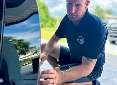 A family sedan with doors open, technicians cleaning both interior and exterior in a spotless service bay, with bright lighting highlighting the car’s renewed appearance and attention to detail.