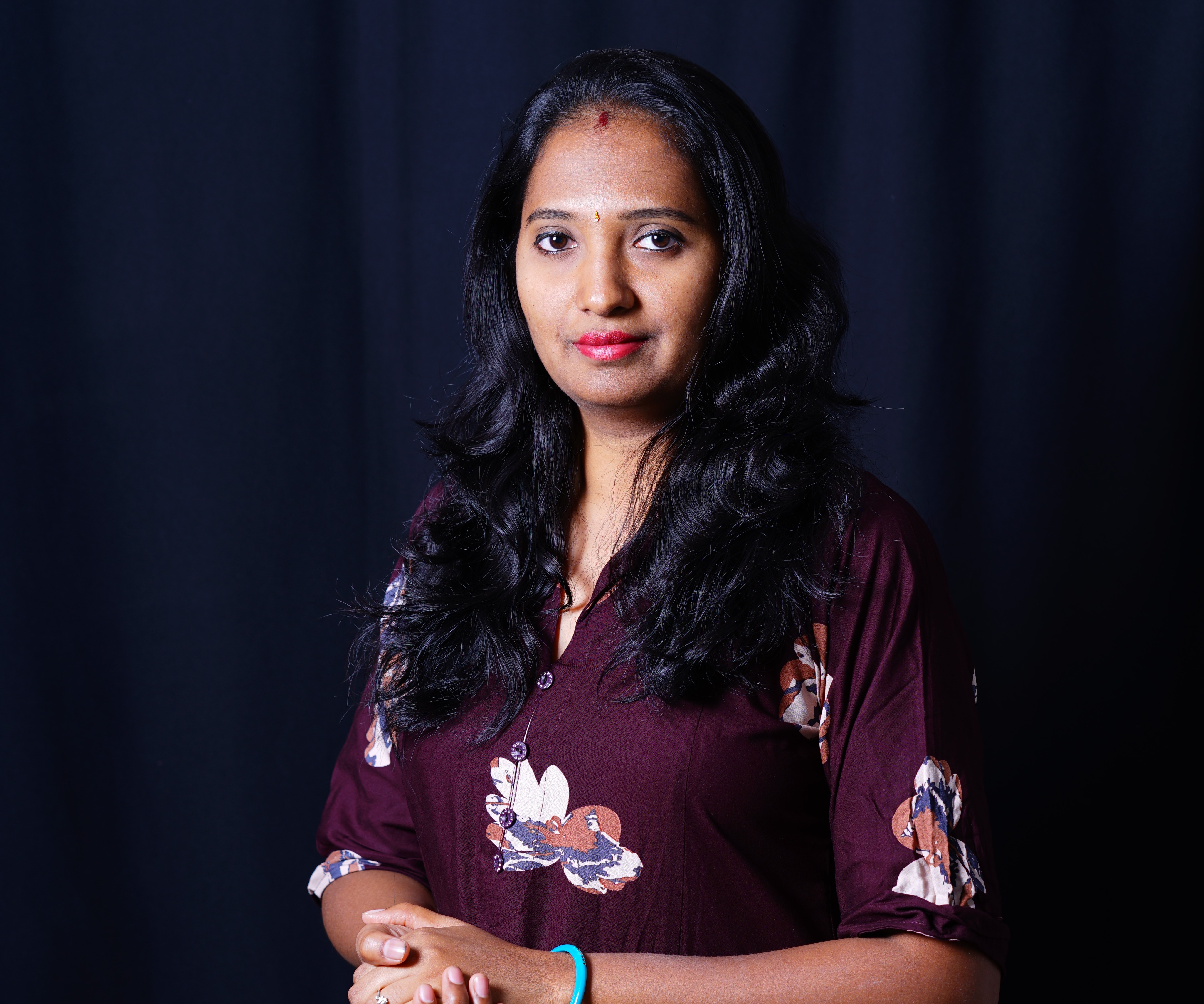 A confident Tamil mother in her 30s, smiling and working on a creative project at a sunlit desk, surrounded by vibrant colors and inspirational notes, symbolizing transformation and empowerment.