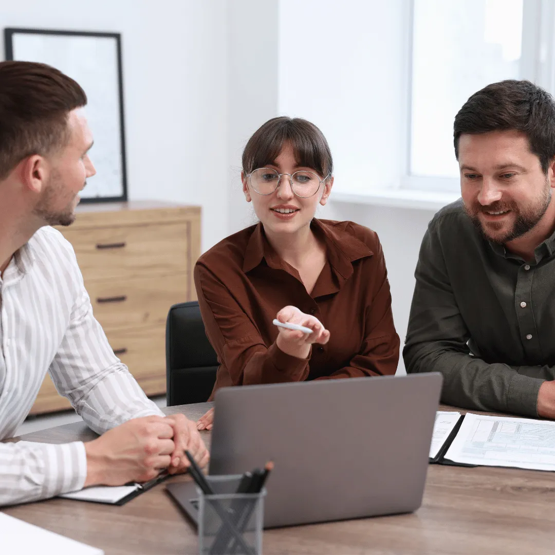  Financial advisors collaborating on a laptop to review business strategy and client data.