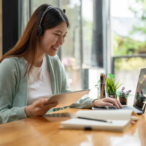 Happy woman working on her laptop with a headset on She looks like she's enjoying her work.