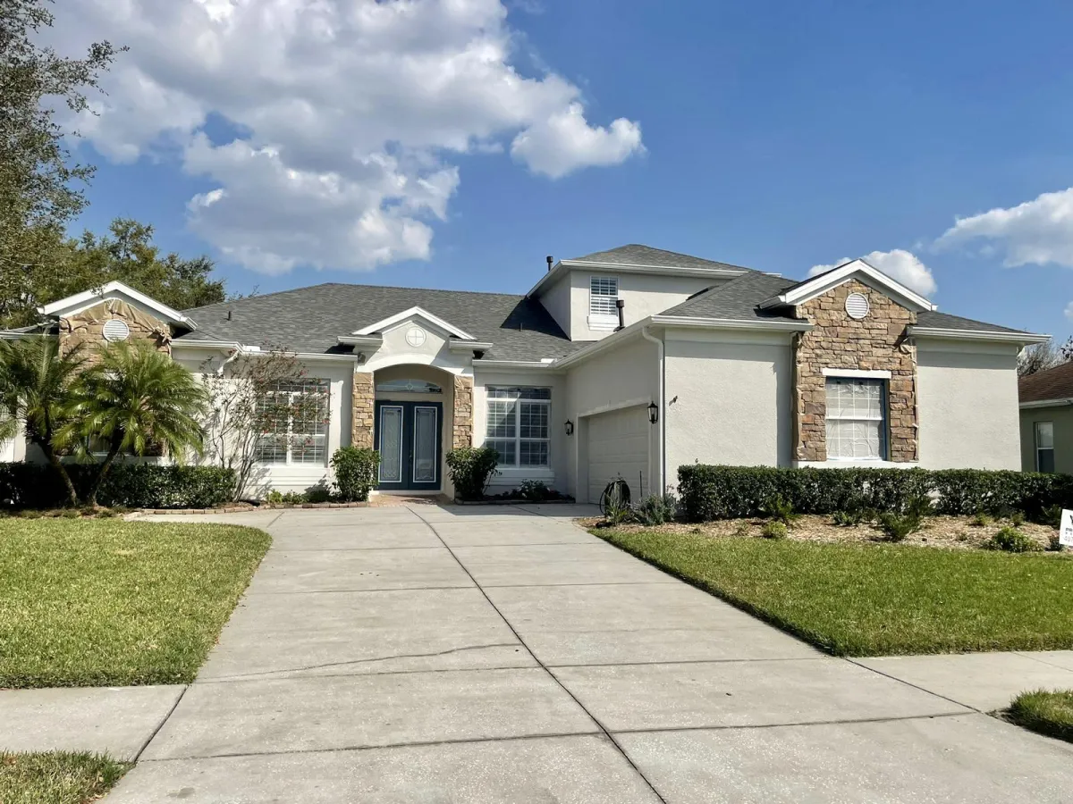 A one story house painted in A home pained in Clermont Florida grey. the home features rock accents on the pillars and around the windows.