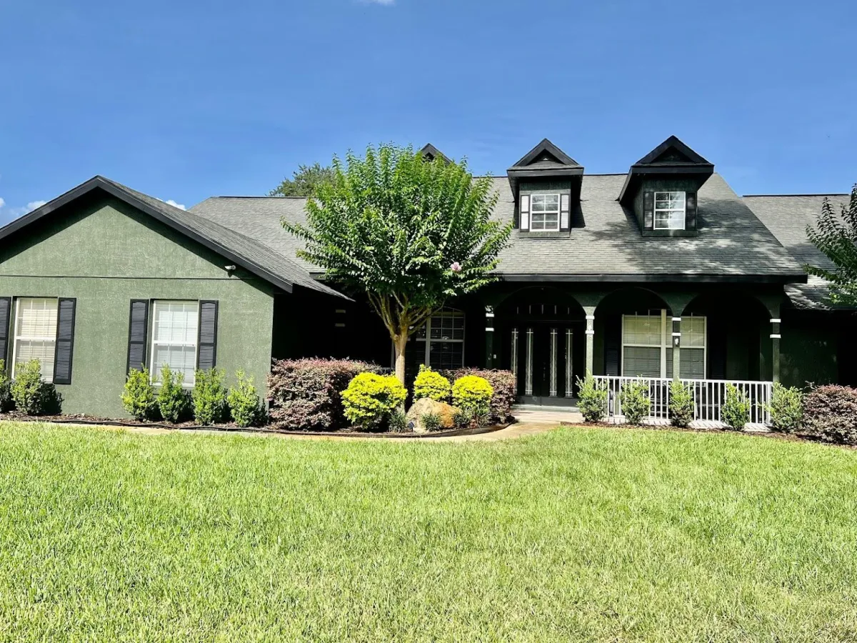 Front view of a farm style house painted dark green by pro painting services.