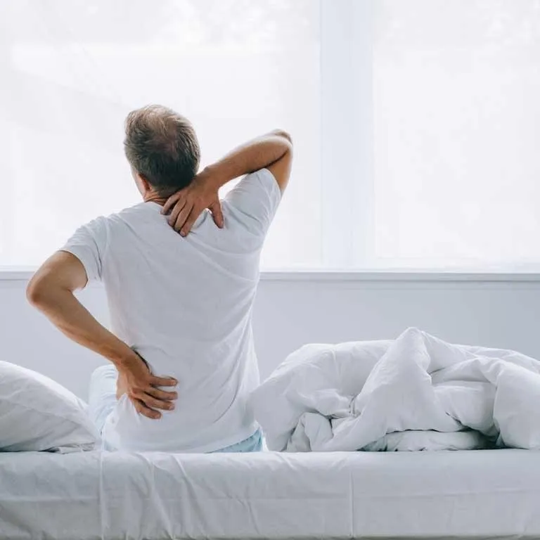 Man sitting on bed with back pain