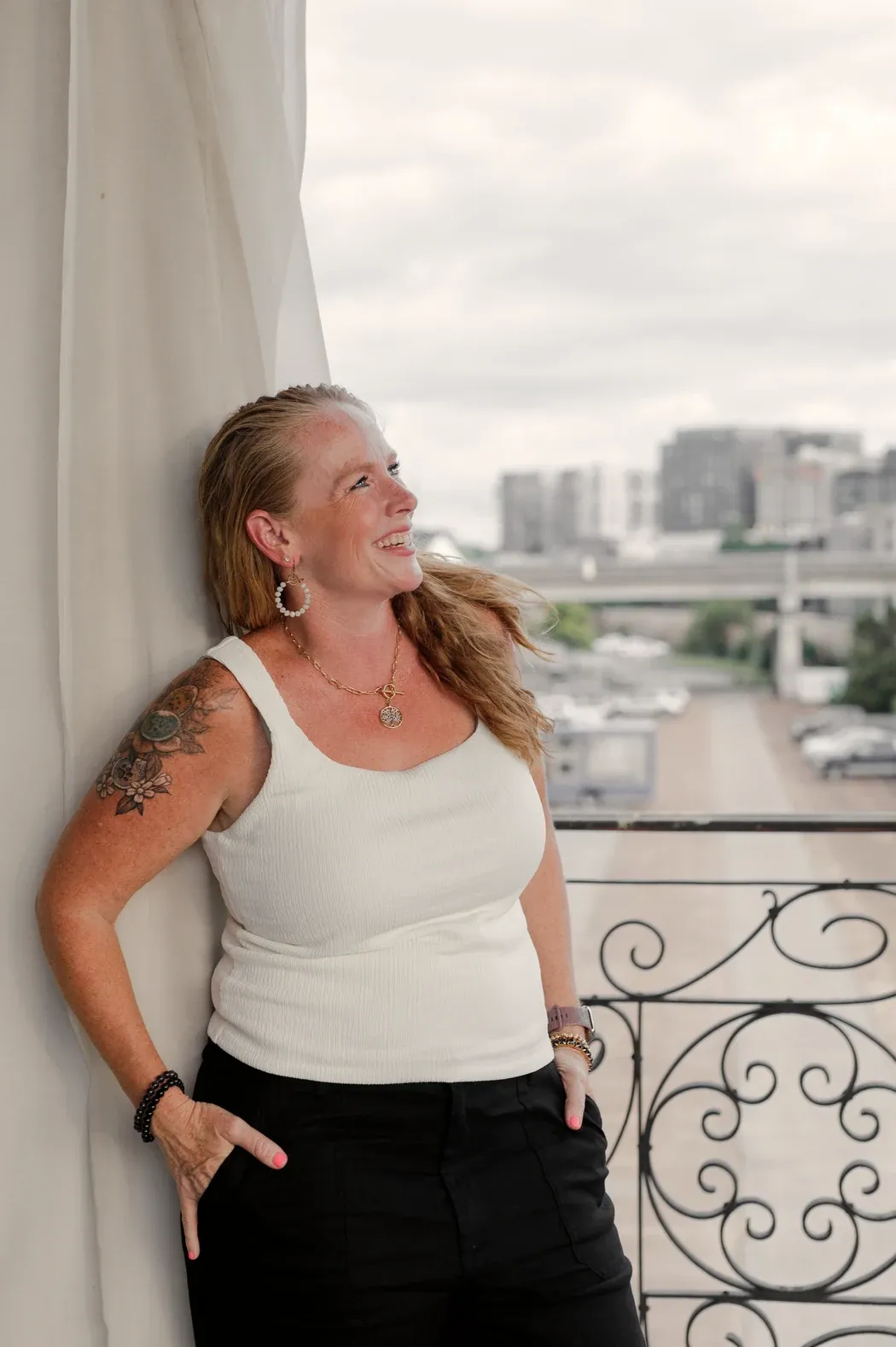 Becca Powers® standing by an open window in Nashville, looking out over the city in quiet reflection