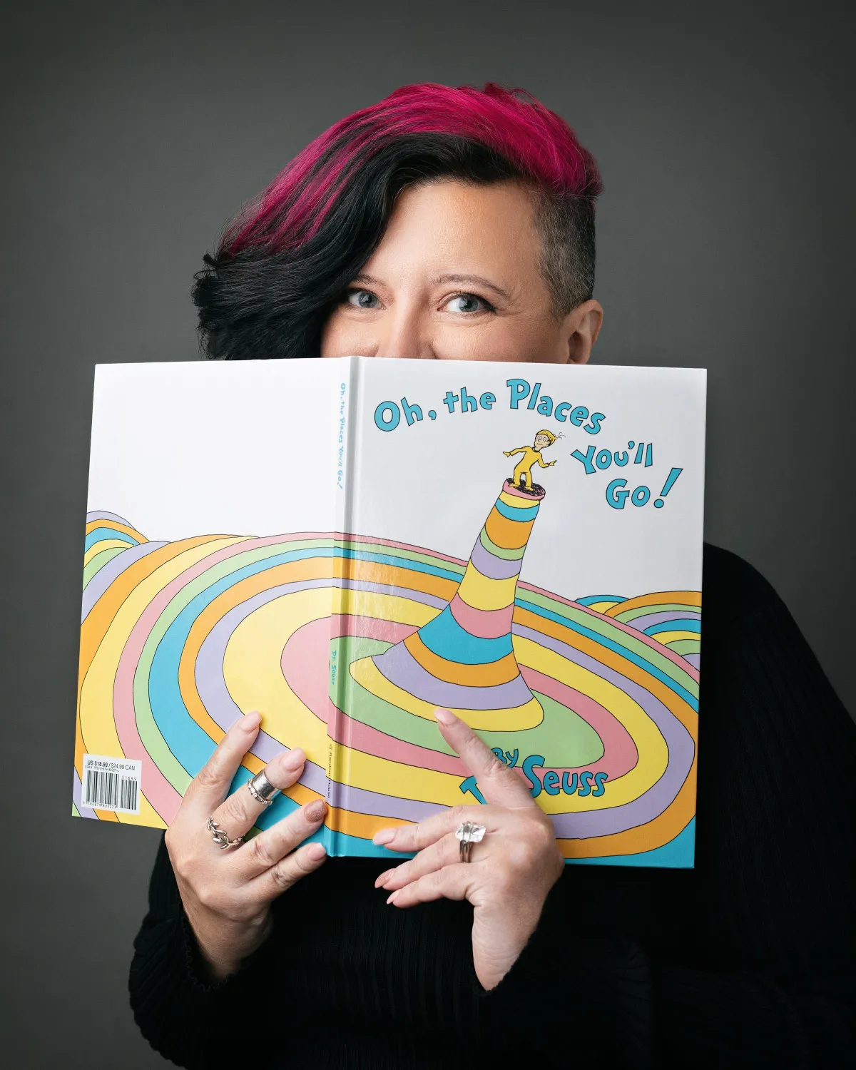 Vanessa Cardenas, Betrayal Recovery Specialist, holding Dr. Seuss' book 'Oh, the Places You'll Go!' on the about page, symbolizing the journey of healing and personal growth.