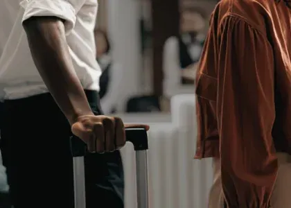 Couple standing with luggage in a hotel lobby during a family vacation while navigating the emotional impact of betrayal.