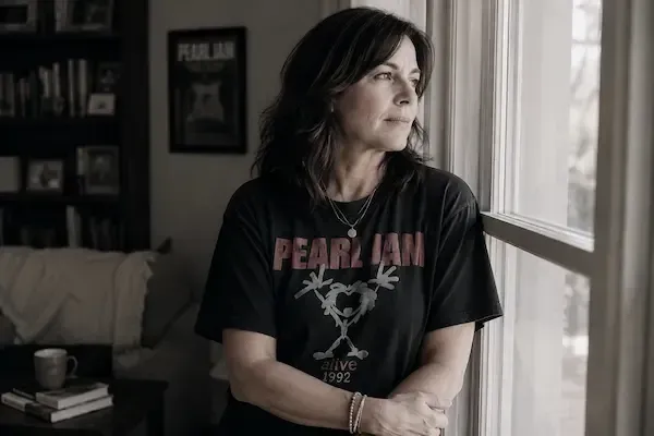 Gen X woman in a vintage Pearl Jam concert T-shirt looking thoughtfully out a window, reflecting on her marriage and what she wants next.