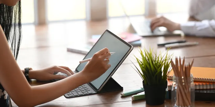 A diverse group of real estate professionals gathered around a table, discussing documents and smiling. The office is decorated with EXIT Elite Realty branding, and the atmosphere is collaborative and supportive. 3:2 aspect ratio.