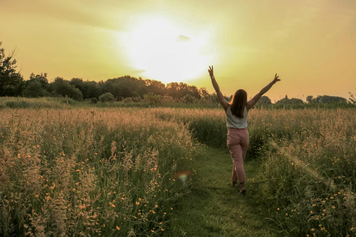 A woman sits in a chair, eyes closed, while another woman in a black blazer performs a hypnosis session on her.