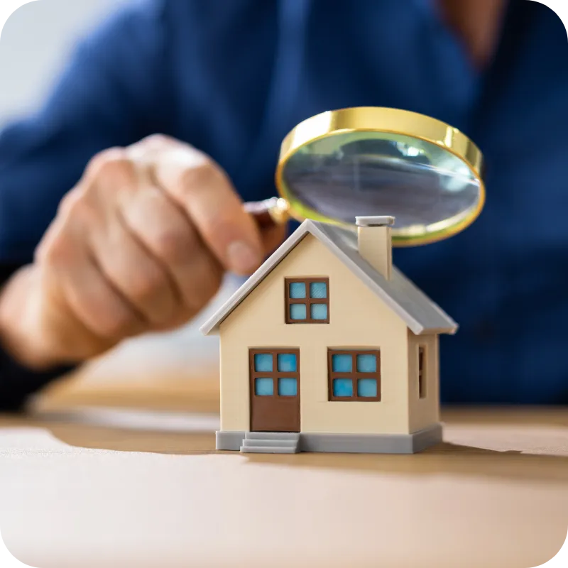 Magnifying glass over house model representing trusted home inspection in Wilmington, DE by Quality Home Inspections.
