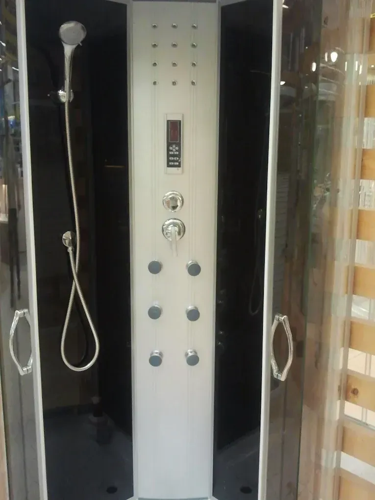 Egy fekete hátfalas, modern hidromasszázs zuhanykabin belseje látható. Középen egy fehér zuhanypanel található digitális kijelzővel, krómozott kezelőgombokkal és hat darab kerek masszázsfúvókával. Bal oldalon egy krómozott kézizuhany lóg a tartóján, a kabin nyitott ajtói pedig átlátszó üvegből készültek, fém fogantyúkkal.