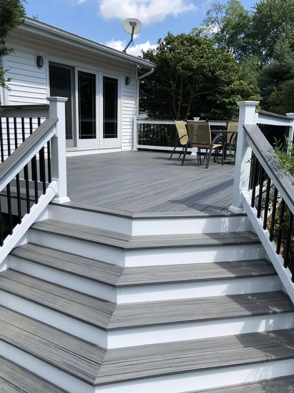 Gray composite deck with white railings and wide white-trimmed steps up to sliding doors | Prime Decks Delaware, serving North Star, DE