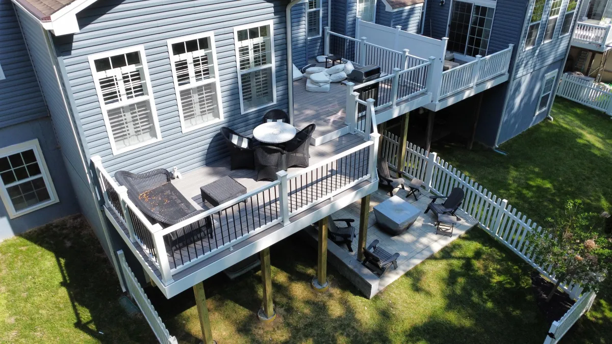 Gray composite deck with white railings, outdoor seating and a grill on a blue-sided home | Prime Decks Delaware, serving Pike Creek, DE