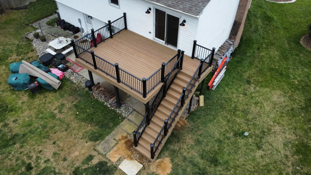 Aerial view of a tan composite deck with black aluminum railings and a long staircase on a white home in Wilmington, DE