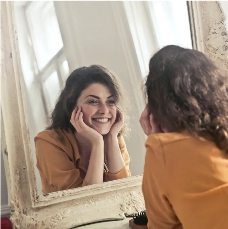 woman smiling into mirror