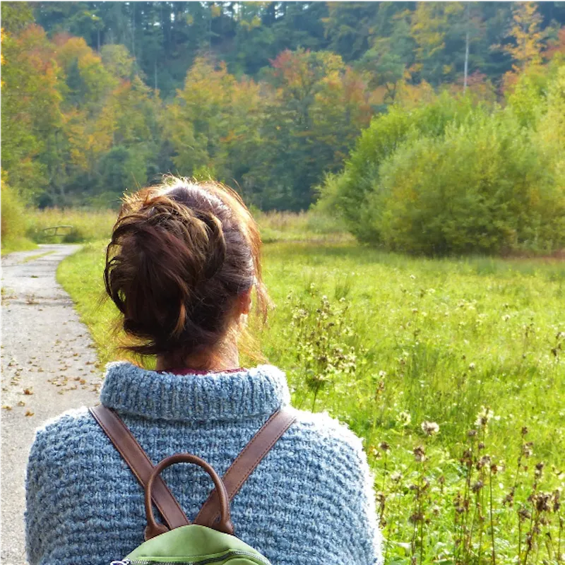 woman with backpack looking at grass