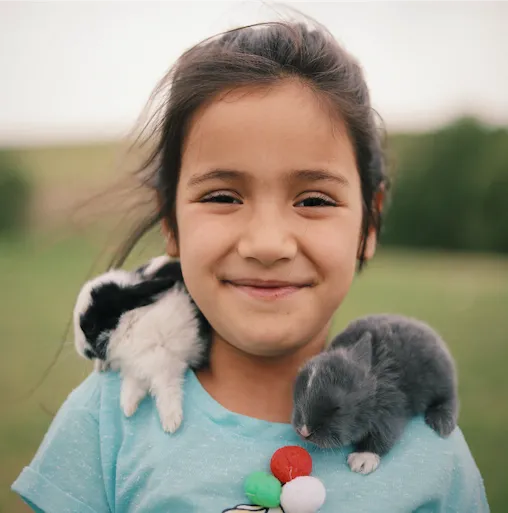 A child with two small pets on her shoulders, showing the close bond many families form with their small pets