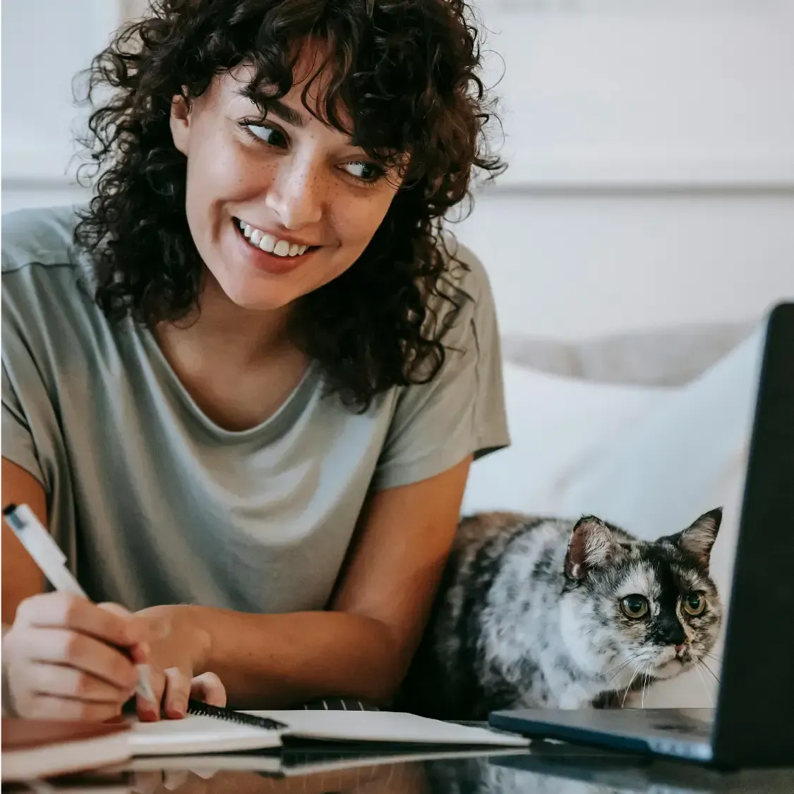 smiling woman with a cat looking at computer