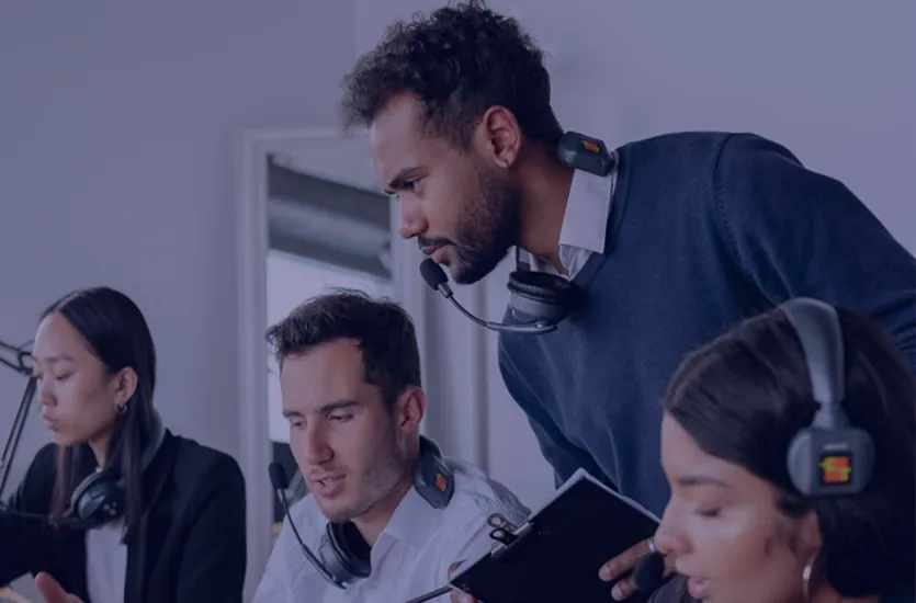Customer support team in a busy office working together calmly and focused, wearing headsets at their computers