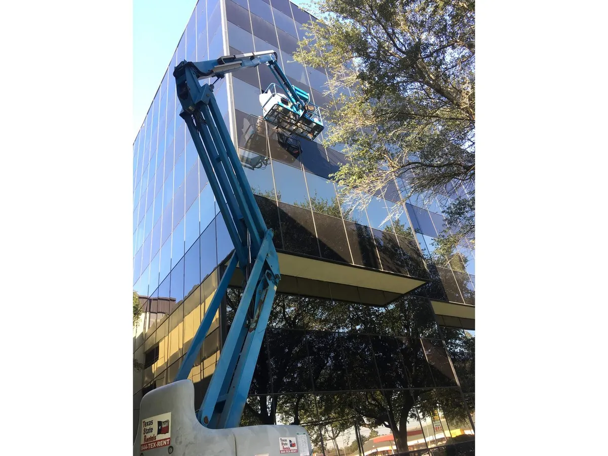 Crane lifting a large glass panel onto a commercial facade