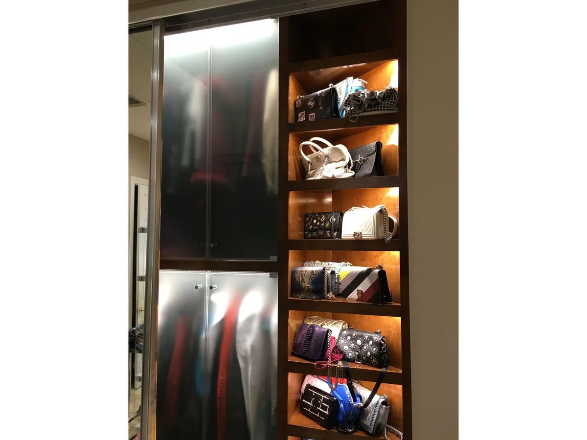Glass shelving displaying handbags in a custom closet