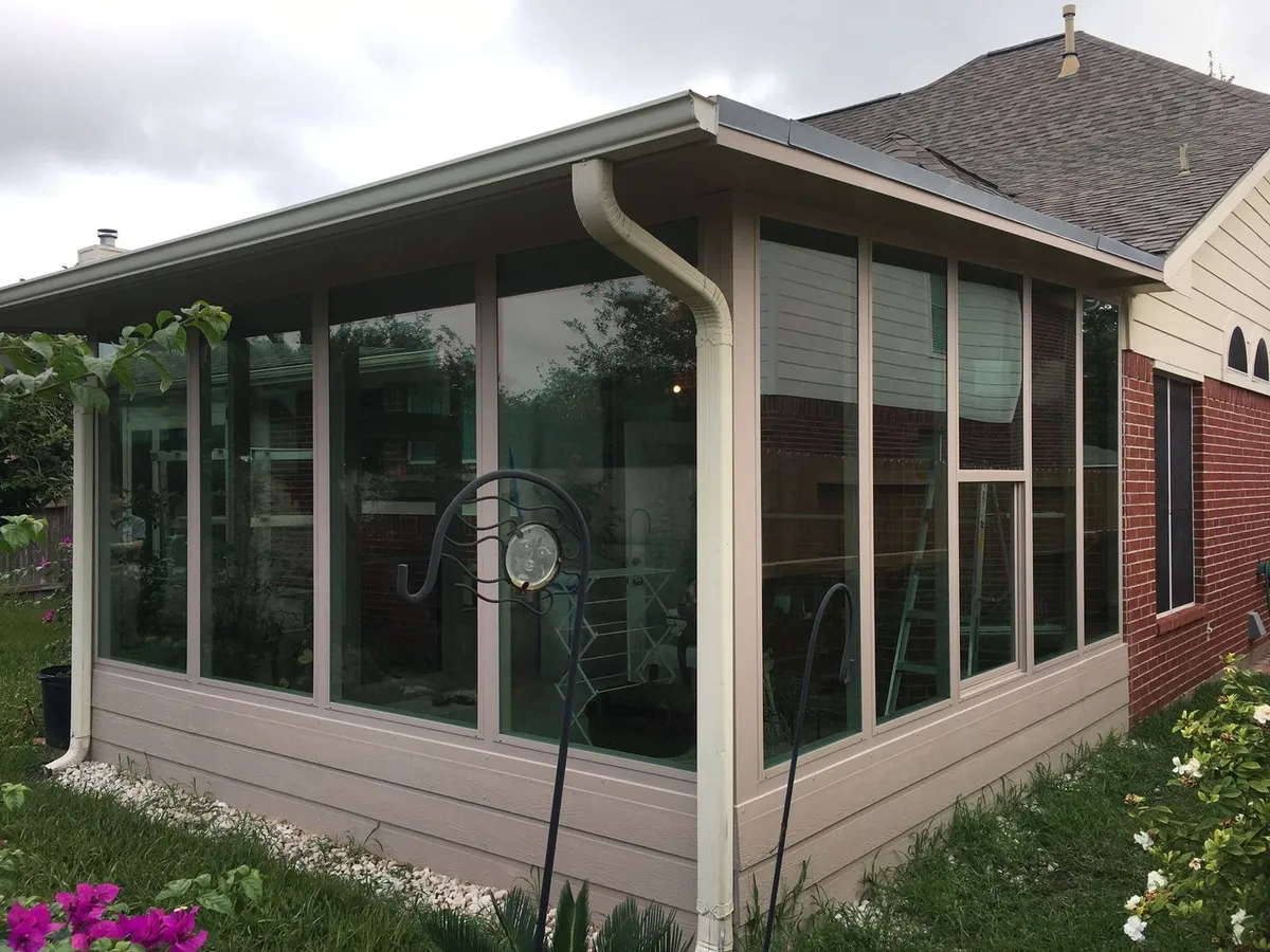 Glass sunroom enclosure on a brick home