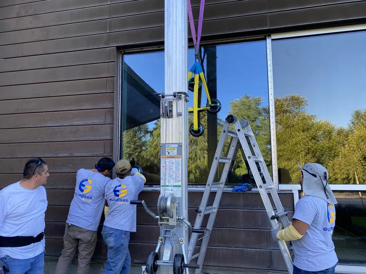 Technicians replacing a commercial window with a suction lifter