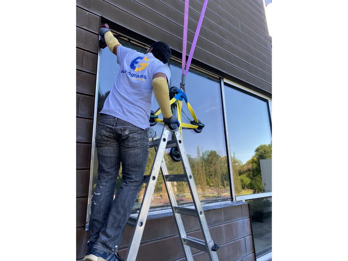 Technician setting a large storefront window on a commercial building