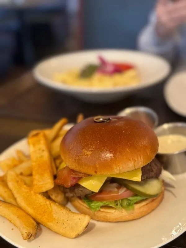 Hamburger on a white plate with french fries on the side