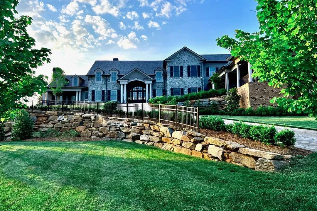 Stone retaining wall and driveway in front of a luxury home built by Mundo Landscaping in Tucson, AZ — expert hardscaping and curb appeal design.