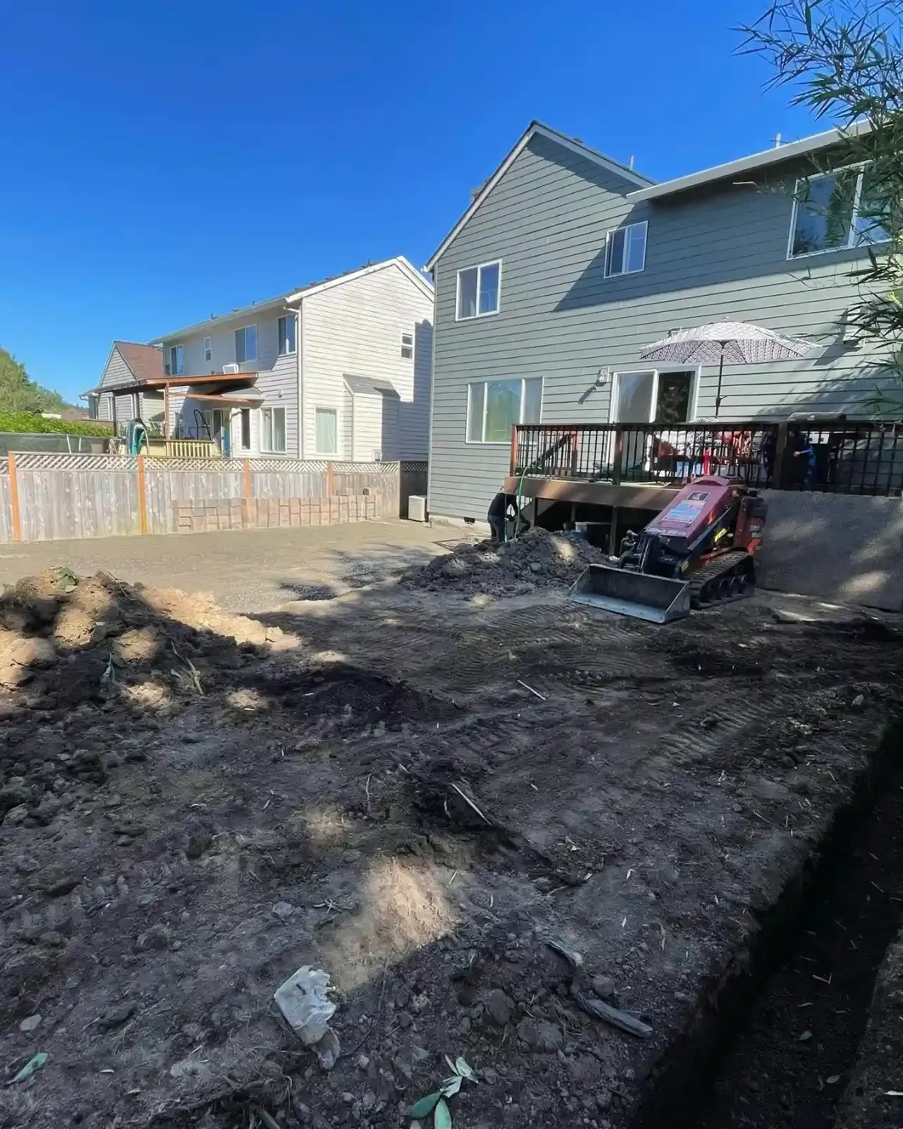 HD Landscape mini skid steer grading a backyard during early excavation for a patio installation in Lake Oswego