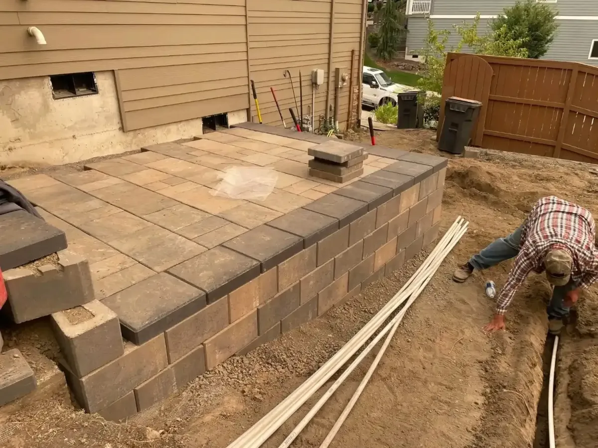 HD Landscape crew building a raised paver platform with block retaining wall and drainage pipe in Wilsonville