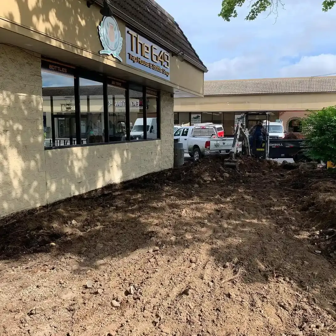 HD Landscape crew and mini excavator clearing a commercial storefront landscape bed in Portland