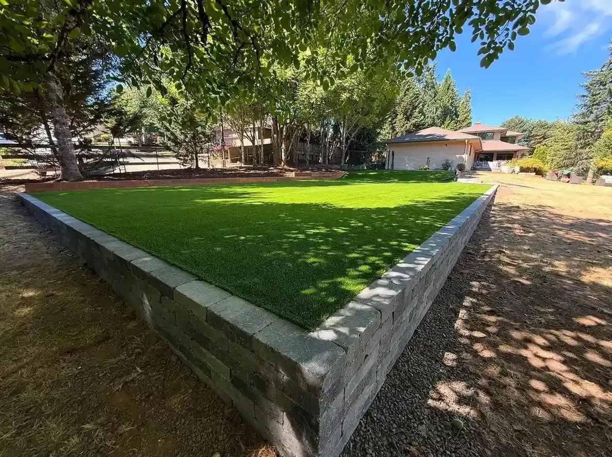 Raised block retaining wall platform with artificial turf on a large acreage lot by HD Landscape in Newberg