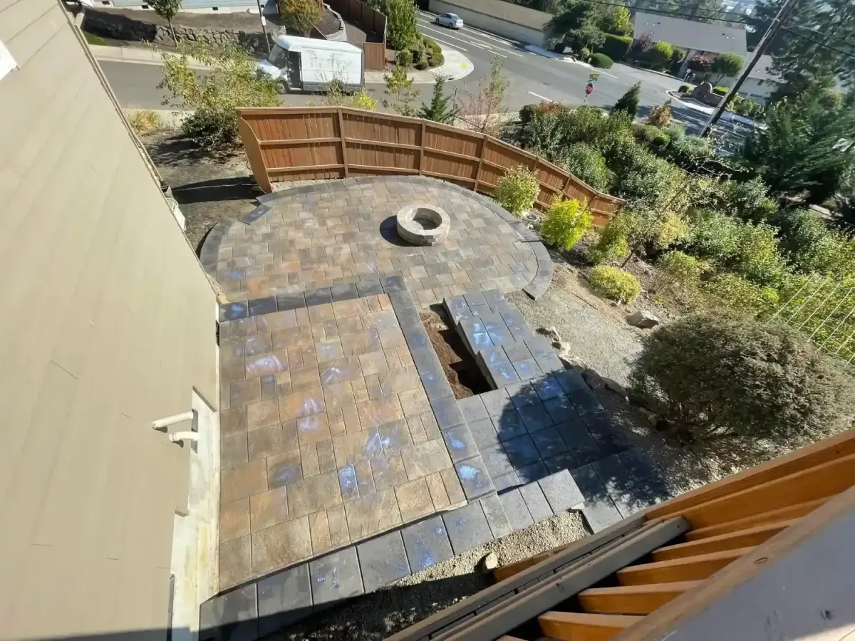 Aerial view of custom paver patio with circular fire pit and wood privacy fence by HD Landscape in Lake Oswego