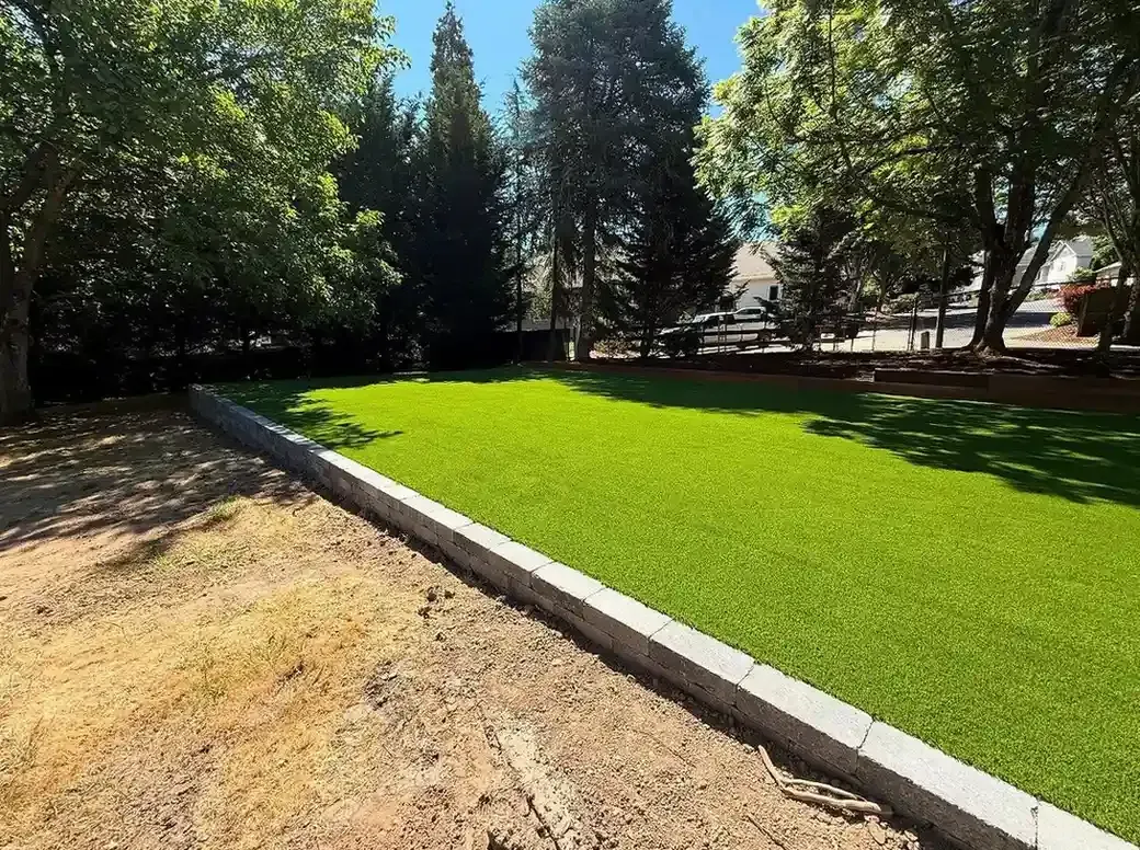Fresh sod installation with concrete block retaining wall border in residential Portland backyard by HD Landscape