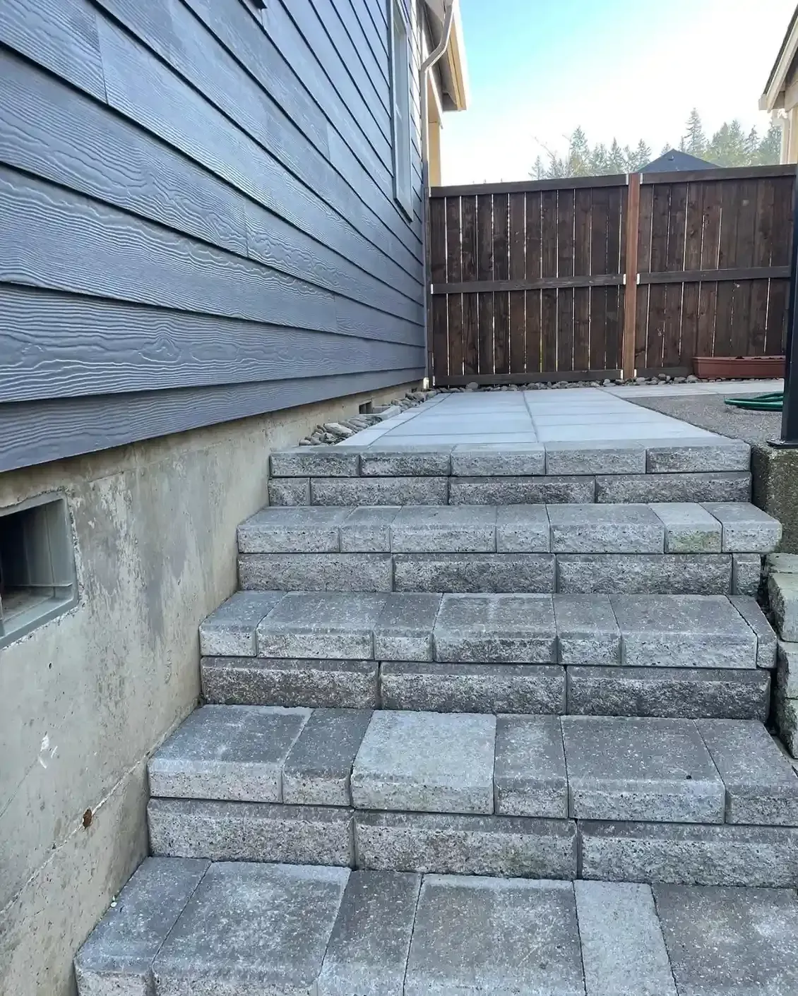 Block paver staircase with large format paver landing and river rock border by HD Landscape in Hillsboro