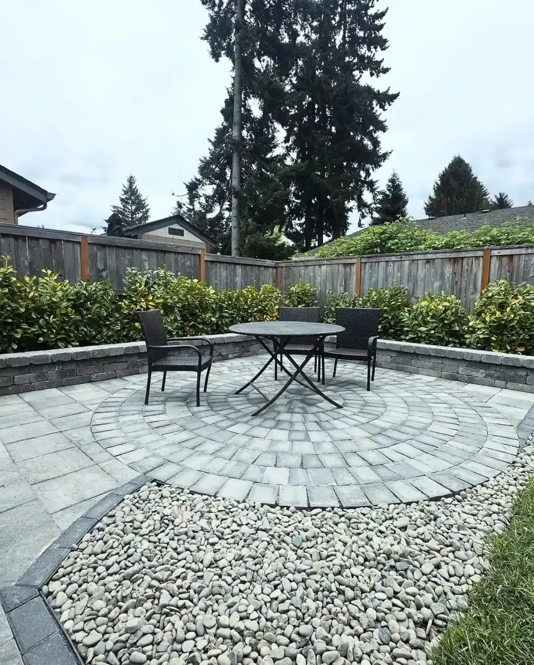 Circular paver patio with wraparound block seating wall and outdoor dining set by HD Landscape in West Linn