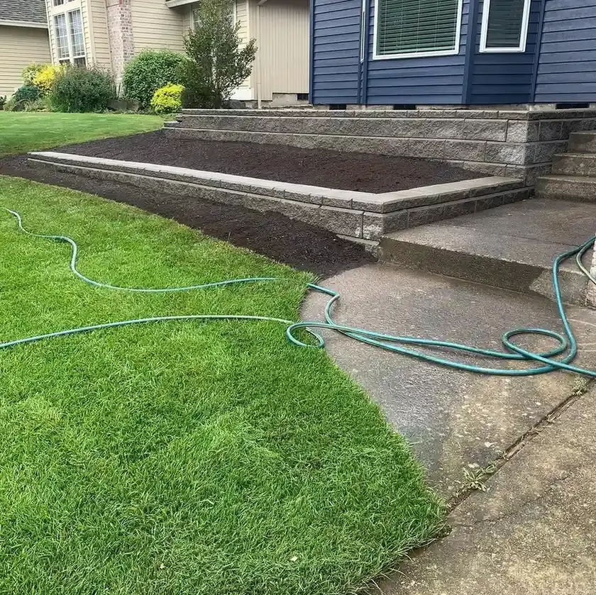 Block retaining wall with capped raised planter bed, fresh mulch, and new sod installation by HD Landscape in Beaverton