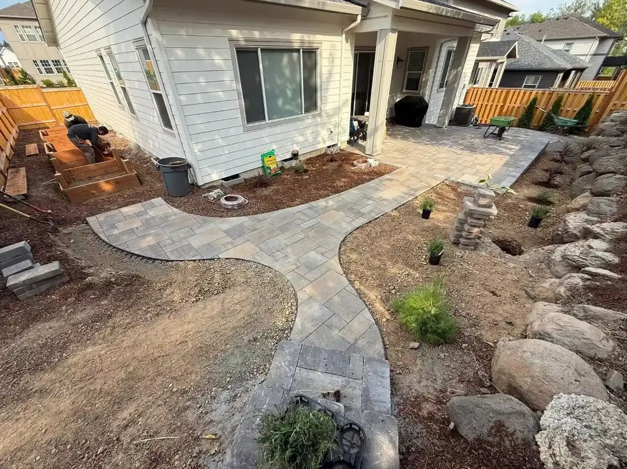 Curved paver patio and walkway with raised cedar garden beds, boulder accents, and new plantings by HD Landscape in Sherwood