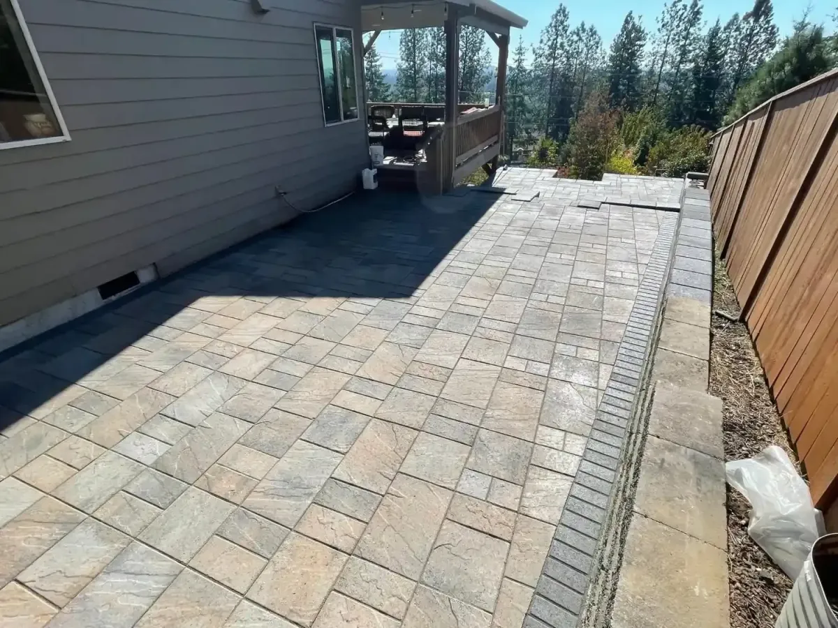 Completed large format paver patio with pergola and wooded hillside view installed by HD Landscape in West Linn