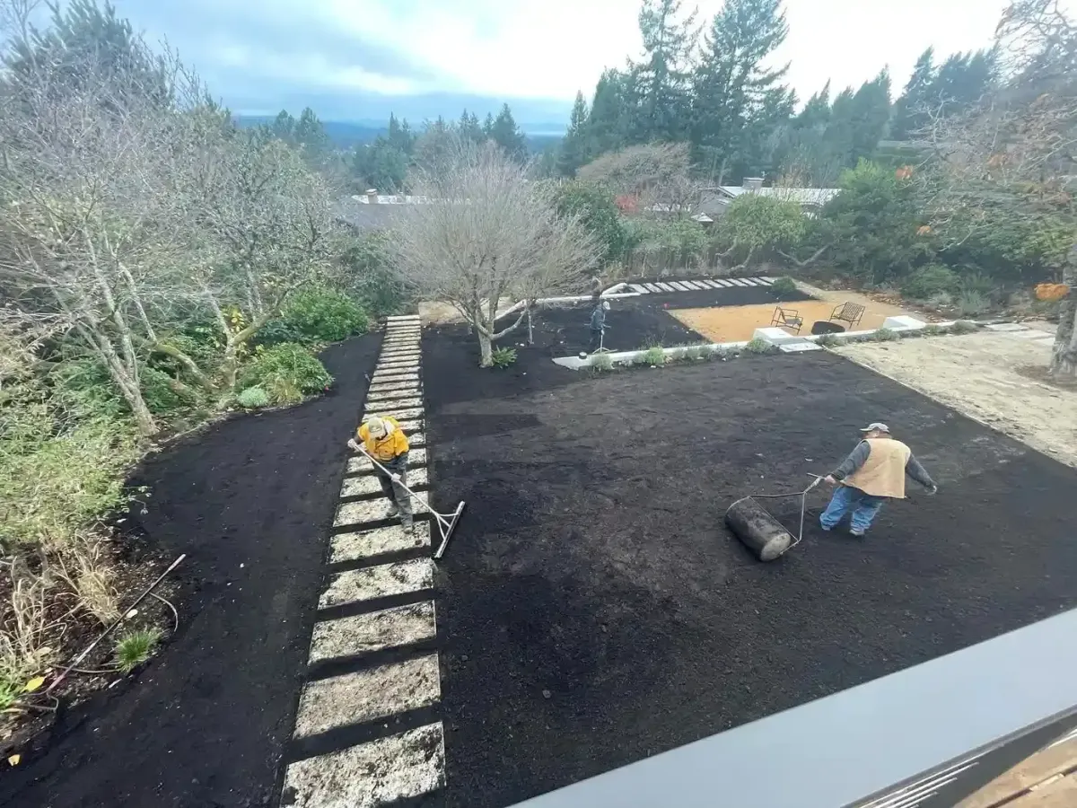 HD Landscape three-man crew raking and rolling topsoil for lawn installation on a large hillside property in West Linn