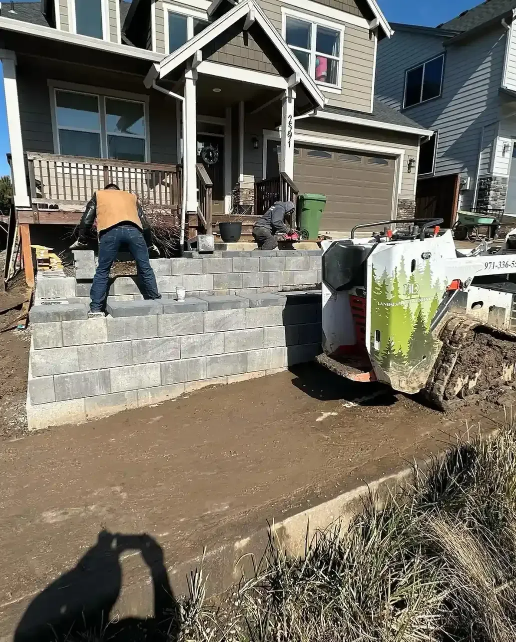 HD Landscape crew laying a block retaining wall with branded skid steer on a front yard renovation in Beaverton