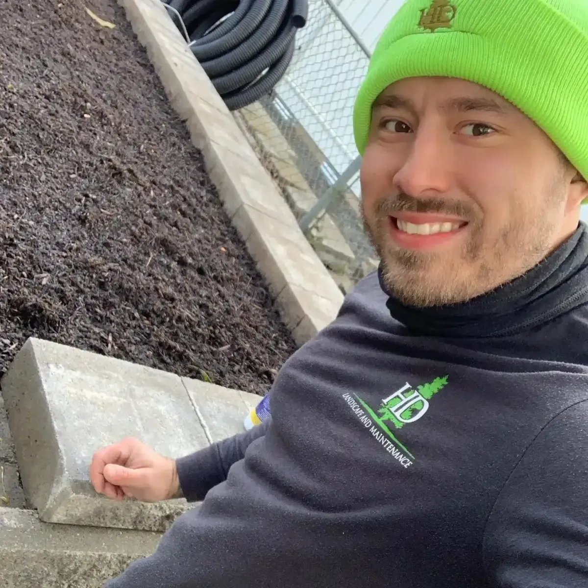 HD Landscape and Maintenance crew member laying curbing beside a fresh mulch bed on a hardscaping job